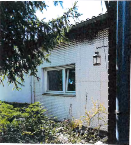 Zwangsversteigerung Einfamilienhaus in Hünfeld – Außenansicht des Wohnhauses mit starker Bepflanzung und davor geparktem Fahrzeug.