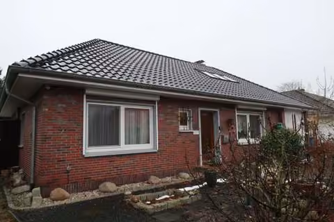 Zwangsversteigerung Einfamilienhaus in Westerstede – Nordostansicht des Walmdachbungalows mit Vorgarten.