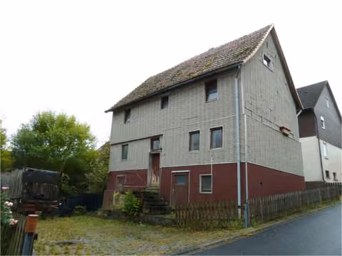 Zwangsversteigerung Einfamilienhaus in Rotenburg a.d. Fulda, Erkshausen – Seitenansicht des Wohnhauses und des gepflasterten Hofbereichs.