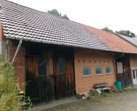 Zwangsversteigerung Zweifamilienhaus in Hohenroda, Glaam – Hauptansicht des zweigeschossigen Wohnhauses mit der Faserzementverkleidung.