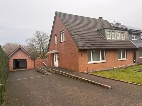 Zwangsversteigerung Doppelhaushälfte in Reken, Maria Veen – Straßenansicht der Doppelhaushälfte mit Garage.
