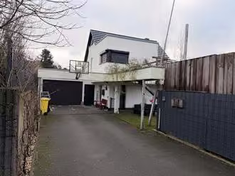 Zwangsversteigerung Einfamilienhaus in Ibbenbüren – Straßenansicht des Hauses von Norden mit der integrierten Garage.