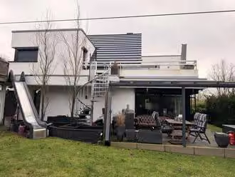 Zwangsversteigerung Einfamilienhaus in Ibbenbüren – Gartenansicht mit Terrasse und Außentreppe zum Obergeschoss.