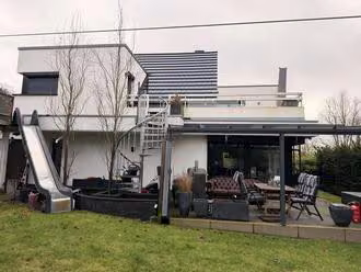 Zwangsversteigerung Einfamilienhaus in Ibbenbüren – Gartenansicht mit Terrasse und Außentreppe zum Obergeschoss.