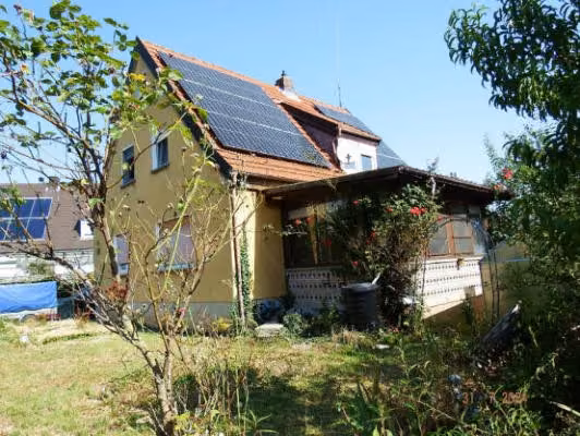 Zwangsversteigerung Einfamilienhaus in Sand am Main – Rückwärtige Ansicht des Gebäudes mit Gartenfläche und Terrasseneinhausung.