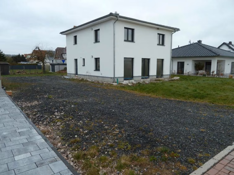 Zwangsversteigerung Einfamilienhaus in Wildeck, Obersuhl – Seitenansicht des Hauses mit geschotterter Hoffläche.