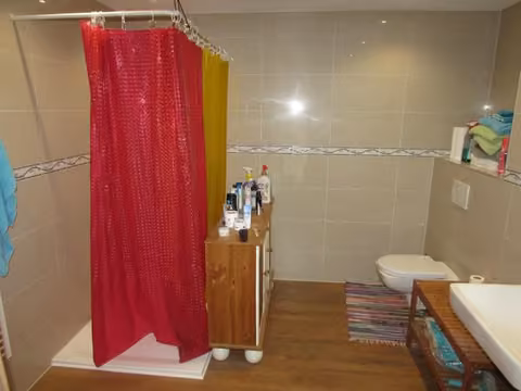 Zwangsversteigerung Eigentumswohnung in Bergisch Gladbach, Gronau – Modernisiertes, hell gefliestes Badezimmer mit bodengleicher Dusche.