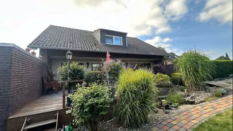 Zwangsversteigerung Einfamilienhaus in Dinslaken, Oberlohberg – Nord-Ansicht mit der aufgestnderten Holzterrasse und dem gepflegten Gartenbereich.