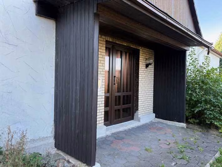 Zwangsversteigerung Zweifamilienhaus in Löhne, Mennighüffen – Hauseingang im Detail mit Holzverkleidung.