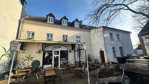 Zwangsversteigerung Büro in Alpen – Rückwärtige Ansicht mit der gastronomisch genutzten Terrasse im Außenbereich.