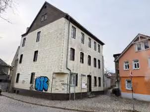 Zwangsversteigerung Mehrfamilienhaus in Saalfeld – Straßenseitige Vorderansicht des Mehrfamilienhauses von links.