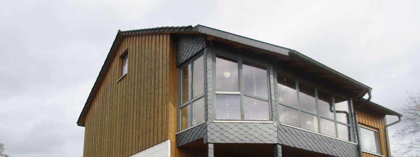 Zwangsversteigerung in Stockheim – Süd-West-Ansicht des Gebäudes mit dem angebauten Wintergarten im Obergeschoss.