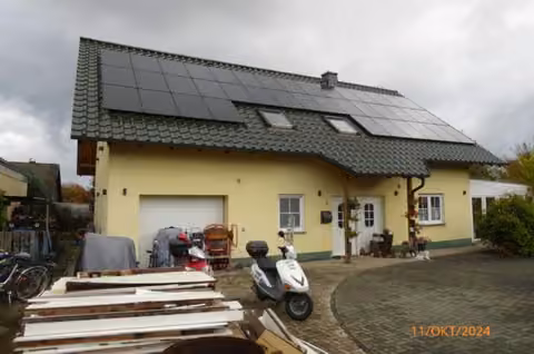 Zwangsversteigerung Einfamilienhaus in Stadtallendorf, Erksdorf – Straßenansicht des freistehenden Einfamilienhauses mit PV-Anlage auf dem Dach.