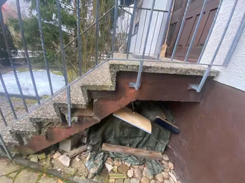 Zwangsversteigerung Einfamilienhaus in Reckendorf – Detailaufnahme der schadhaften Stahlbeton-Unterkonstruktion der Eingangstreppe.