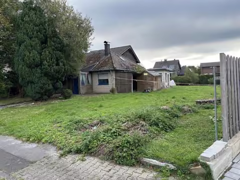 Zwangsversteigerung Eigentumswohnung in Hürtgenwald, Vossenack – Vorderansicht der Wohnung Nr. 2 mit baufälligem Wintergarten-Anbau.