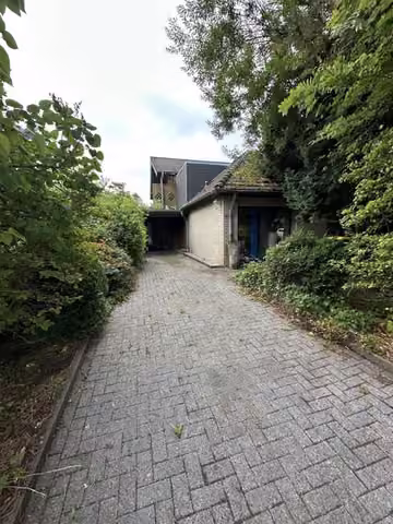 Zwangsversteigerung Eigentumswohnung in Hürtgenwald, Vossenack – Zufahrt zum Objekt und seitliche Außenansicht mit Garage.