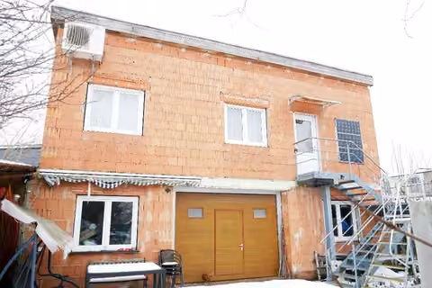 Zwangsversteigerung Einfamilienhaus in Großneuhausen – Hinterhaus - Westansicht der unverputzten Ziegelmauer mit angehängter Stahltreppe.
