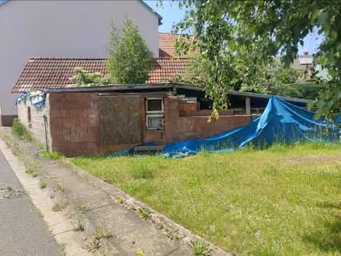 Zwangsversteigerung in Birstein, Böß-Gesäß – Aussenansicht der Bauruine mit Notüberdachung und blauer Plane.