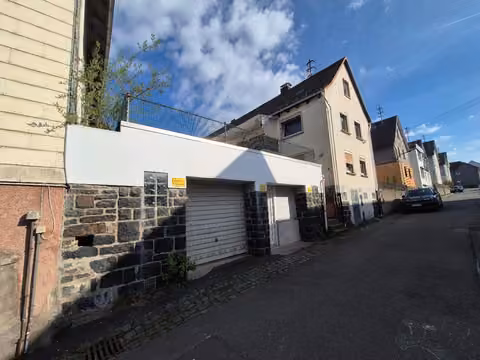 Zwangsversteigerung Einfamilienhaus in Biedenkopf, Wallau – Außenansicht mit Garage und Terrasse.