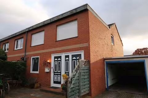 Zwangsversteigerung Reihenhaus in Westerstede – Nordostansicht des Reihenendhauses mit Eingangsbereich und Garage.