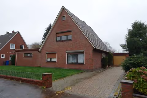 Zwangsversteigerung Einfamilienhaus in Westerstede – Vorderansicht des Einfamilienhauses mit Auffahrt und Garage.