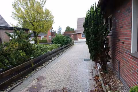 Zwangsversteigerung Einfamilienhaus in Westerstede – Gepflasterte Auffahrt und seitlicher Zugang zum Grundstück.
