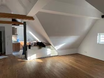 Zwangsversteigerung Eigentumswohnung in Köln, Klettenberg – Helles Wohnzimmer mit Holzdielenboden und offener Kochecke.