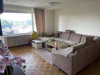 Zwangsversteigerung Eigentumswohnung in Bielefeld, Sennestadt – Wohnzimmer der Wohnung Nr. 7 mit Parkettboden und Fensterfront zur Loggia.