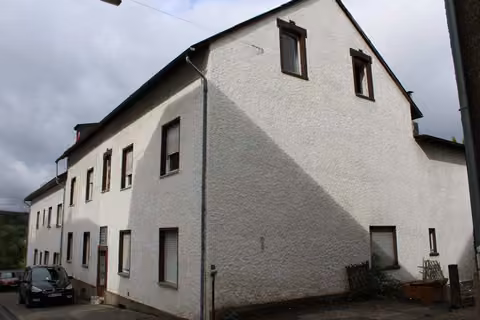 Zwangsversteigerung Eigentumswohnung in Wirges – Nord-Ansicht des Mehrfamilienhauses mit Thujahecke.