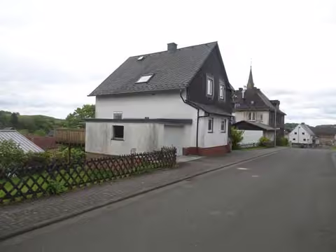 Zwangsversteigerung Einfamilienhaus in Bad Endbach, Bottenhorn – Außenansicht von Nordwesten mit Garage und Balkon.