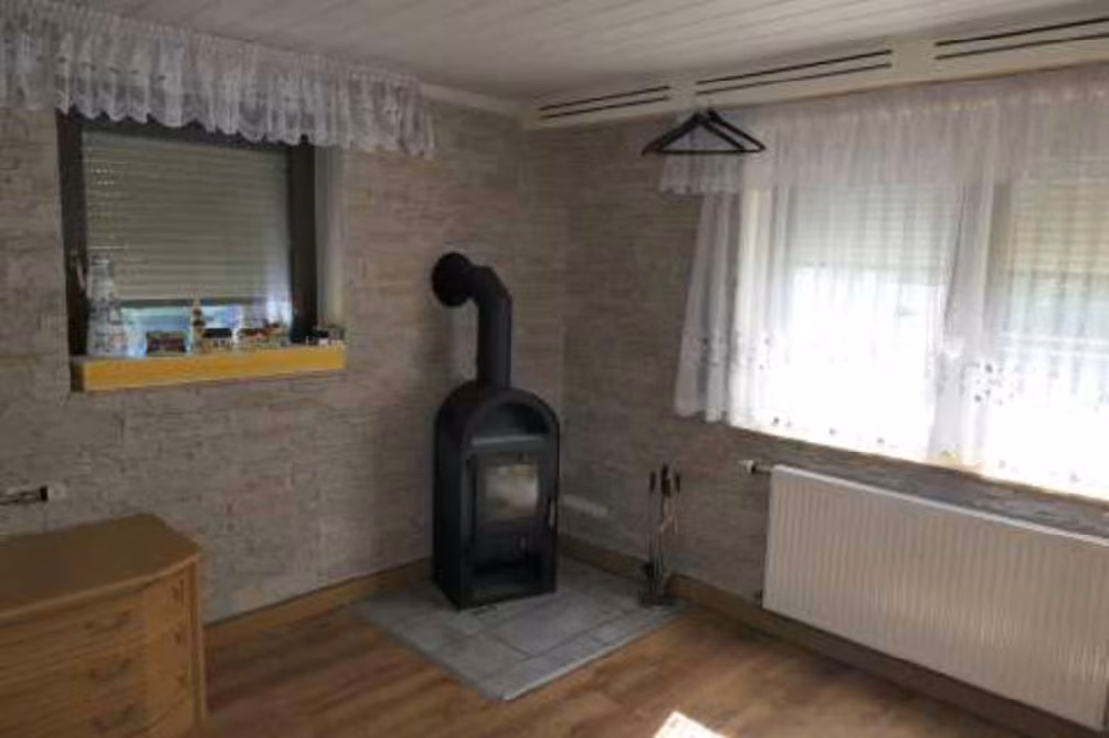 Zwangsversteigerung Einfamilienhaus in Schwarzenbach am Wald, Sorg – Wohnraum im Anbau auf Kellerebene mit Kaminofen.