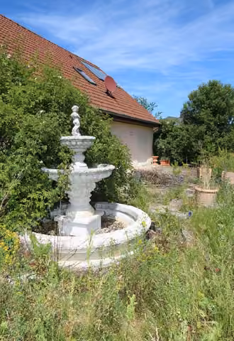 Zwangsversteigerung Einfamilienhaus in Poppenricht – Gartenbereich mit aufgestelltem Zierbrunnen.