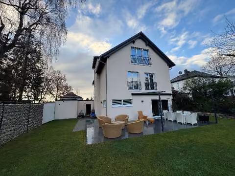 Zwangsversteigerung Einfamilienhaus in Kelkheim, Kelkheim-Mitte – Gartenseitige Rückansicht des Hauses mit Terrasse und Rasenfläche.