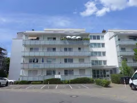 Zwangsversteigerung Eigentumswohnung in Mörfelden-Walldorf, Walldorf – Frontansicht der Wohnanlage Schwarzwaldstraße 7-11 von Osten mit davorliegenden Parkplätzen.