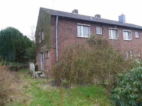 Zwangsversteigerung Zweifamilienhaus in Kempen – Frontansicht der Doppelhaushälfte Blatendoop 27 mit Klinkerfassade und Gartenbewuchs.