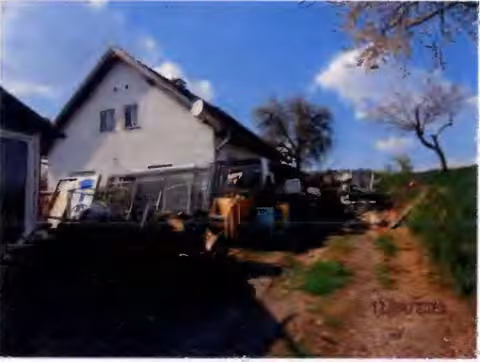 Zwangsversteigerung Einfamilienhaus in Arnstorf, Döttenau – Südansicht des Wohnhauses mit Zufahrtsweg über das Nachbargrundstück.