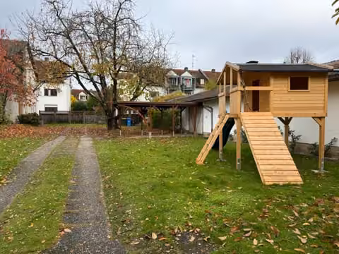Zwangsversteigerung Einfamilienhaus in Simbach am Inn – Östlicher Grundstücksbereich mit Zufahrtsspuren und Carport/Nebengebäude.