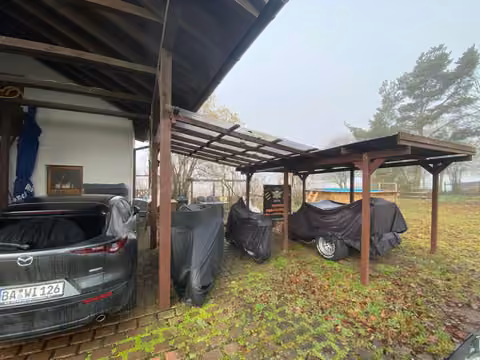 Zwangsversteigerung Mehrfamilienhaus in Breitengüßbach – Holzcarport und überdachte Stellplatzsituation seitlich des Gebäudes.
