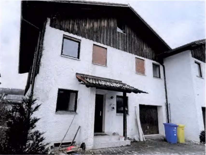 Zwangsversteigerung Reihenhaus in Burgkirchen, Hirten – Nordansicht des Wohnhauses mit Hauseingang und integrierter Garage.