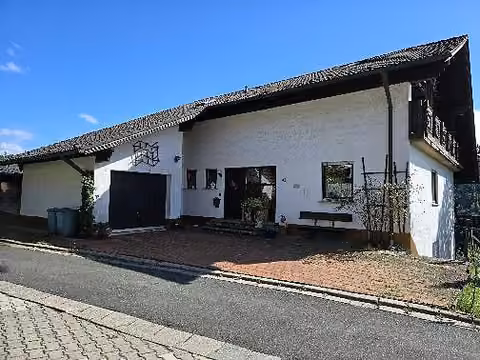 Zwangsversteigerung Wohn-/Geschäftshaus in Steinwiesen – Nordwestansicht des Wohn- und Geschäftshauses mit angebauter Garage und Zufahrtsbereich.