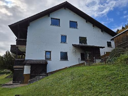 Zwangsversteigerung Wohn-/Geschäftshaus in Steinwiesen – Nordostfassade mit Hangabböschung und rückwärtigem Grundstückszugang.