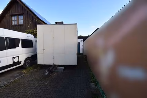 Zwangsversteigerung Einfamilienhaus in Baiersdorf, Wellerstadt – Detailansicht der Massivgarage mit blauem Schwingtor und Hauseingangsbereich.