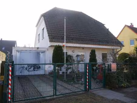 Zwangsversteigerung Einfamilienhaus in Berlin, Blankenburg – Straßenseitige Frontansicht des Einfamilienhauses mit Hauseingang und angebauter Grenzgarage.