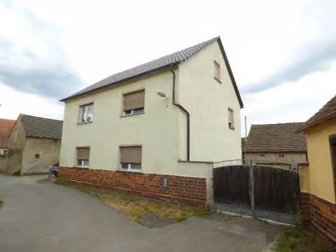 Zwangsversteigerung Zweifamilienhaus in Ruhland – Straßenansicht des Zweifamilienhauses auf Flurstück 1591 mit Toranlage auf Flurstück 810.