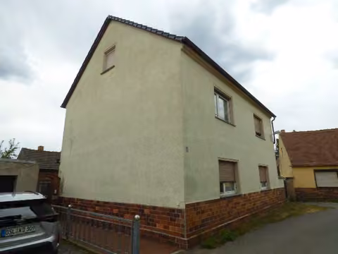 Zwangsversteigerung Zweifamilienhaus in Ruhland – Ansicht der Giebelseite des Wohnhauses mit fußläufiger Zuwegung.