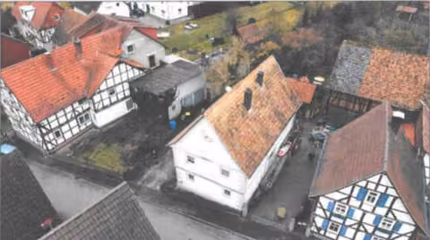 Zwangsversteigerung Zweifamilienhaus in Eschwege, Albungen – Luftbild-Schrägansicht der Gesamtanlage mit Fachwerkhaus, Nebengebäuden und Hof.