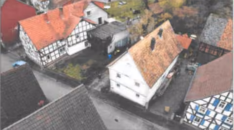 Zwangsversteigerung Zweifamilienhaus in Eschwege, Albungen – Luftaufnahme der straßenseitigen Ostansicht des Wohnhauses und der Nebengebäude.