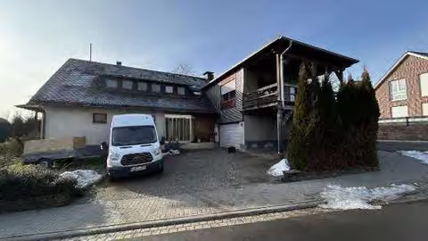 Zwangsversteigerung Einfamilienhaus in Greifenstein, Allendorf – Vorderansicht des Wohnhauses mit Anbau und Garagentor.
