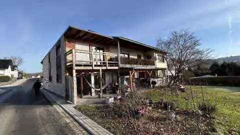 Zwangsversteigerung Einfamilienhaus in Greifenstein, Allendorf – Rückansicht des Objekts mit Balkonen und Gartenbereich.