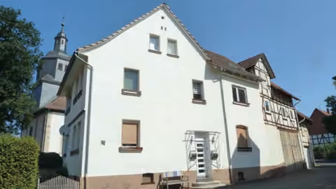 Zwangsversteigerung Einfamilienhaus in Alheim, Heinebach – Vorderansicht des Wohnhauses in der Kirchstraße 17 mit Nachbarbebauung.